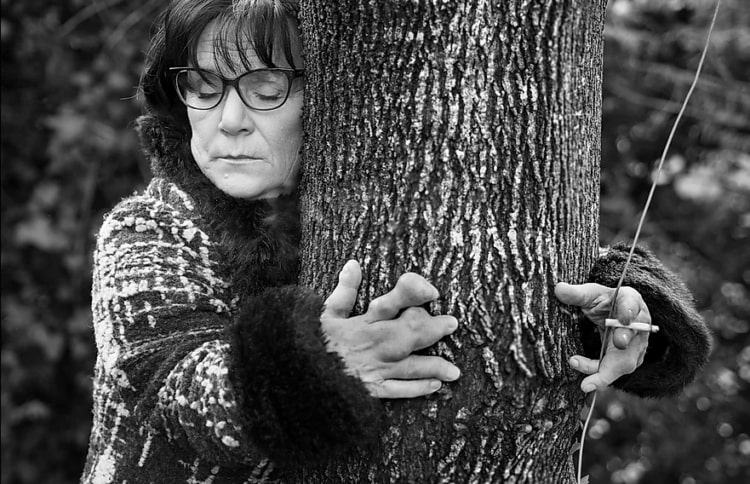 Une femme handicapée enlaçant un arbre.