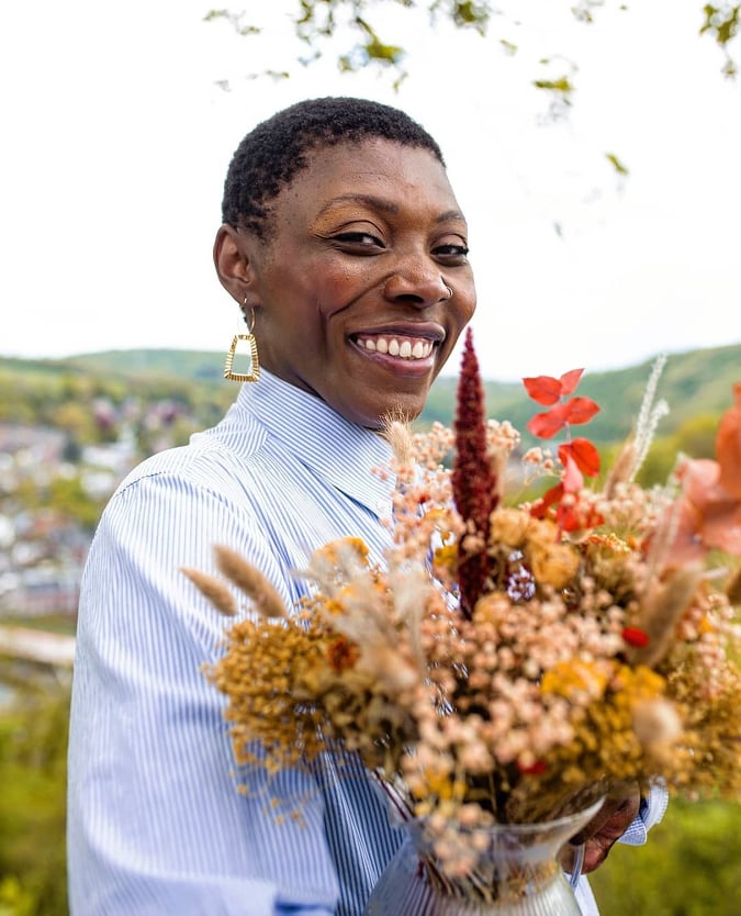 Marianne, sourit à l'objectif en tenant un bouquet champêtre. 